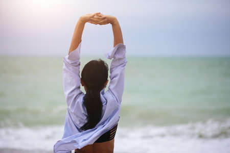 Back view portrait of woman stretching her arms up. Healthy wellness lifestyle. Spiritual health....