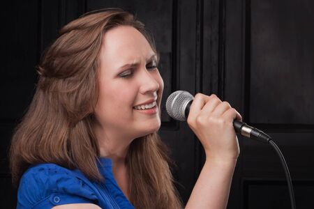 Girl singing to the microphone in a studioの写真素材