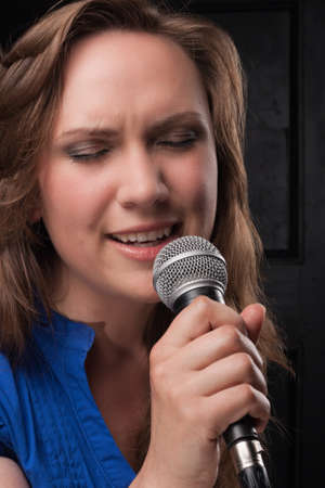 Girl singing to the microphone in a studioの写真素材