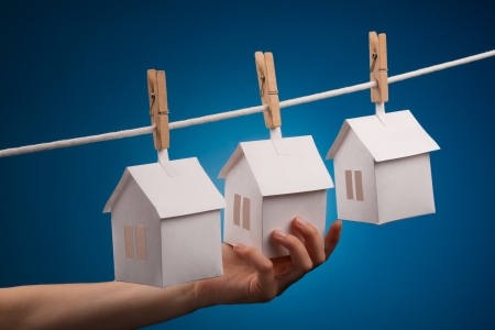 Paper houses with clothespins, hanging from rope on blue background の写真素材