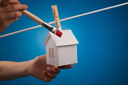 Paper houses with clothespins, hanging from rope on blue background の写真素材