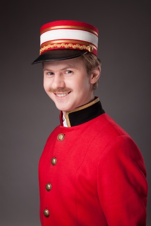 Portrait of a concierge in a red jacket on a gray background の写真素材