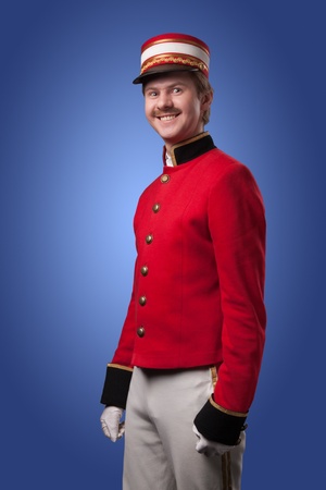 Portrait of a concierge  porter  in a red jacket on a blue background の写真素材