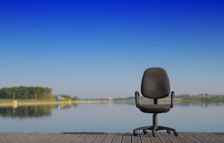 Office chair on the dock by the riverの写真素材