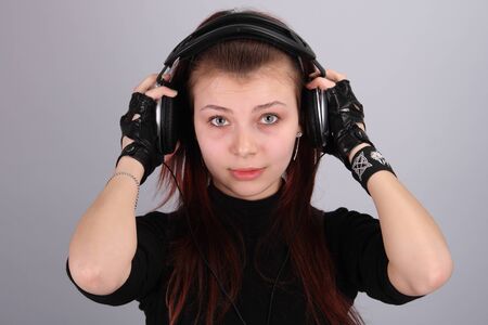 Portrait of the young charming girl with ear-phones and in black glovesの写真素材
