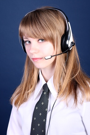The young girl with a fair hair in ear-phones with a microphone and a blouse with a tieの写真素材