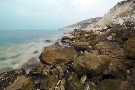Sea landscape with red stones in the foreground and frowning the sky