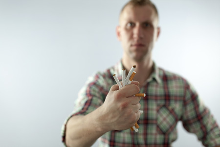 Man trying to quit smoking. Rumple cigarettes in hand Conceptual image.の写真素材