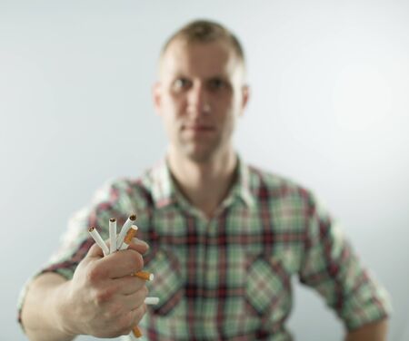 Man trying to quit smoking. Rumple cigarettes in hand Conceptual image.の写真素材
