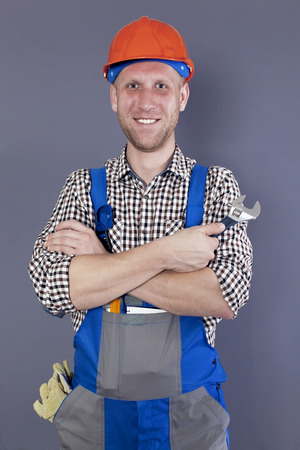 Smiling young worker or plumber in helmet hold wrenchの写真素材