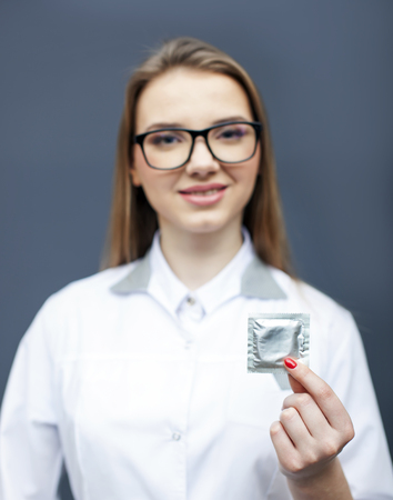 Smiling woman doctor, nurse in glasses with condom on palm. Conceptual imageの写真素材
