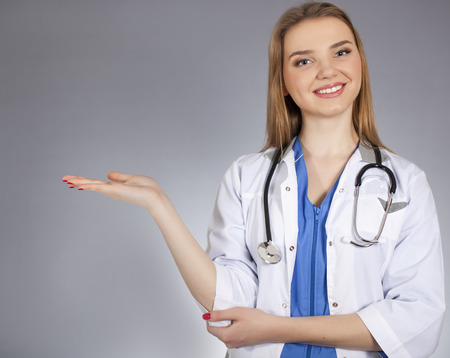 Young attractive woman doctor holds palm horizontal and smile.の写真素材
