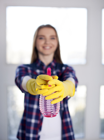 Smiling girl holds detergent bottle in hands. Blurred faceの写真素材