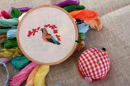 Pin cushion with pins and accessories on a background of gray canvas