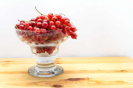 bunch of red currant and glass of fruit-drink juice on a wood table on white backgroundの写真素材