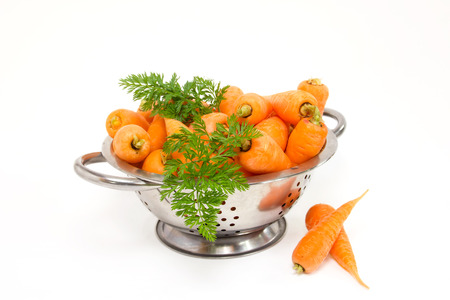 Raw carrots in a colander on a white backgroundの写真素材