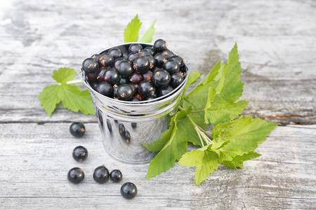 Black currant in a bucket on a wooden backgroundの写真素材