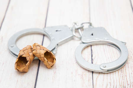 Handcuffs and braided sandals. Poverty drove to jailの写真素材