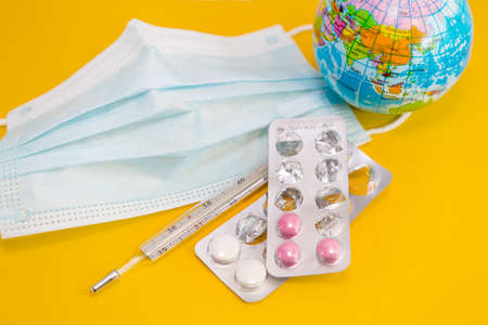 Medical mask, thermometer, pills and globe. Treatment and prevention during the global coronavirus epidemicの写真素材
