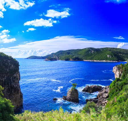 Beautiful summer panoramic seascape. View of the coastline into the sea bays with crystal clear azure water. Lonely rock with a tree on top. A small tree on top. Paleokastrica. Corfu. Greece.の写真素材
