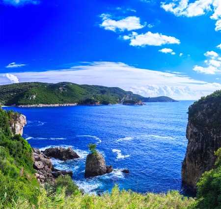 Beautiful summer panoramic seascape. View of the coastline into the sea bays with crystal clear azure water. Lonely rock with a tree on top. A small tree on top. Paleokastrica. Corfu. Greece.の写真素材