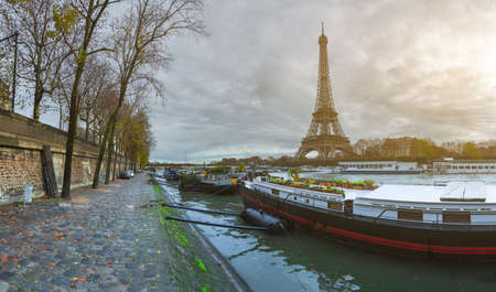 Beautiful panoramic view of the Eiffel Tower and Jena bridge from the river Seine embankment. Dramatic cloudscape. Traditional sitycape in backlit morning sunbeam. Paris, France.の写真素材