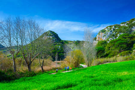The trail, the pedestrian, car-free zone in the valley of the Alcabrichel River, surrounded by evergreen trees on steep hills. People walking along the road. Landscape near Vimeiro in Portugal.の写真素材