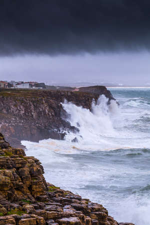 A huge ocean waves breaking on the coastal cliffs in at the cloudy stormy day. Breathtaking romantic seascape of ocean coastline. Peniche, Portugal.の写真素材