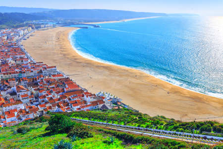 Wonderful romantic afternoon aerial landscape coastline of Atlantic ocean. View Nazare beach riviera(Praia da Nazare) with cityscape of Nazare town in low season at sunny weather. Portugal.の写真素材