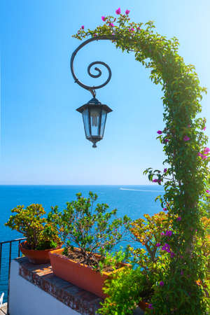 Cute curly lantern wrapped up of blooming bougainvillea. Beautiful summer seascape. Awesome view picturesque hills coastline sea bay with crystal clear azure water in the calm warm sea.の写真素材