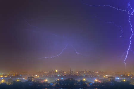 Lightning over the city at the summer storm. Dramatic, breathtaking atmospheric natural phenomenon.の写真素材