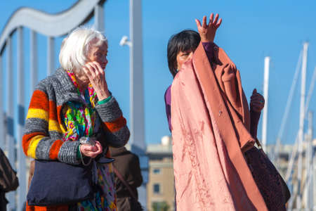 Spain, Barcelona - Jan 01, 2012: People Local and tourists have are rest and relaxing and walk in a leisurely way in a beautiful sunshine warm weather on a seafront Rambla De Mar near Maremagnum mall.のeditorial素材