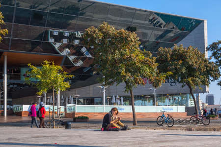 Spain, Barcelona - Dec 29, 2011: People Local and tourists have are rest and relaxing and walk in a leisurely way in a beautiful sunshine warm weather on a seafront Rambla De Mar near Maremagnum mall.のeditorial素材