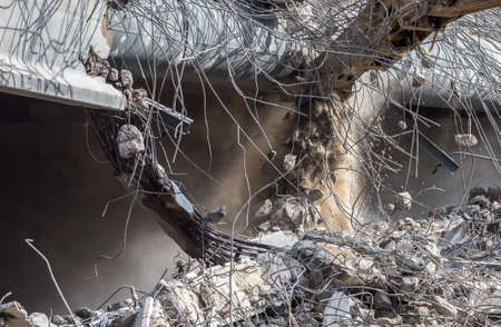 Professional demolition of reinforced concrete structures using industrial hydraulic hammer. Rods of...