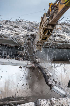 Professional demolition of reinforced concrete structures using industrial hydraulic hammer. Rods of...