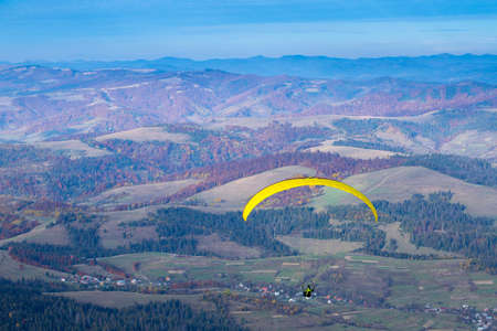 Paraglider flying over Carpathian mountains in summer autumn day. Borzhava. Ukraine.