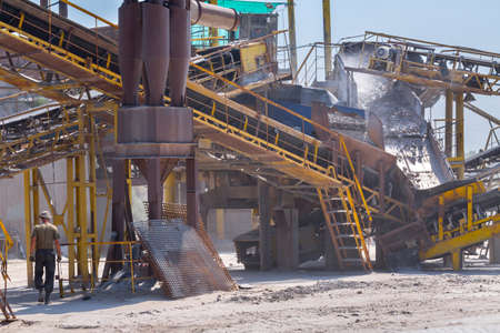 Crushing machinery, cone type rock crusher, conveying crushed granite gravel stone in a quarry open...