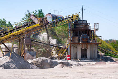 Crushing machinery, cone type rock crusher, conveying crushed granite gravel stone in a quarry open pit mining. Processing plant for crushed stone and gravel. Mining and Quarry mining equipment.の写真素材