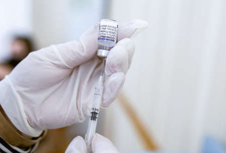Khotyn, Ukraine - OCT 18 2021: Nurse draws a dose of Comirnaty BioNTech-Pfizer vaccine from a vial into a syringe in the vaccination center in the city council. Khotyn, Ukraine, October 18, 2021のeditorial素材