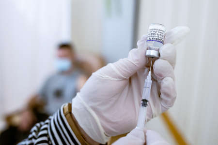 Khotyn, Ukraine - OCT 18 2021: Nurse draws a dose of Comirnaty BioNTech-Pfizer vaccine from a vial into a syringe in the vaccination center in the city council. Khotyn, Ukraine, October 18, 2021のeditorial素材