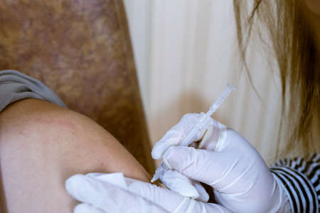 Khotyn, Ukraine - OCT 18 2021: The nurse injects a dose of the Comirnaty BioNTech-Pfizer vaccine the visitor in the vaccination center in the city council. Khotyn, Ukraine, October 18, 2021のeditorial素材