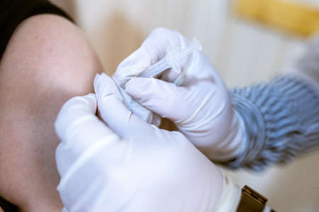 Khotyn, Ukraine - OCT 18 2021: The nurse injects a dose of the Vaxzevria/COVID-19 AstraZeneca vaccine the visitor in the vaccination center in the city council. Khotyn, Ukraine, October 18, 2021のeditorial素材