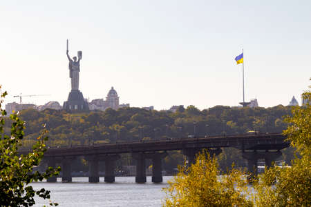Bright evening cityscape of the big city on the hill over wide river Dnipro in awesome bright sunset...