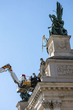 LVIV, UKRAINE - March 21, 2022: To protect the sculptures on the facade of the Lviv National Opera from damage due to possible bombing, rescuers of the SES wrap them with mineral wool and film.のeditorial素材