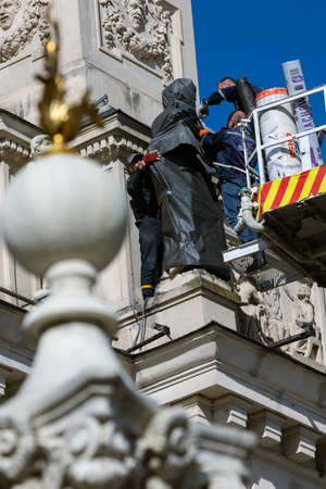 LVIV, UKRAINE - March 21, 2022: To protect the sculptures on the facade of the Lviv National Opera from damage due to possible bombing, rescuers of the SES wrap them with mineral wool and film.のeditorial素材
