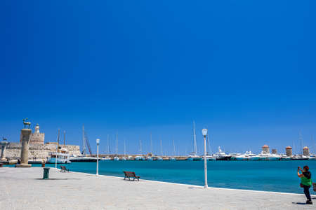Rhodes, Greece - July 04, 2021: Mandraki harbor and marina. Hirsch and Hirschkuh, bronze statues of...
