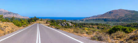 An exciting panoramic view of amazing roads without traffic in at Rhodes, Greece. Beautiful asphalt freeway, motorway, highway through of southern landscape mountains forest at hot weather in mid-Julyの写真素材