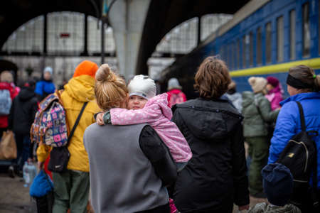 LVIV, UKRAINE - APR 02, 2022: War in Ukraine. Little girl on mom's shoulder. Refugees from the evacuation train from Mariupol, Berdyansk, Kryvyi Rih, are flees to Europe at the Lviv Railway Station.のeditorial素材