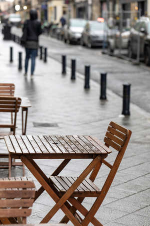 An empty outdoor area of a traditional french restaurant or cafe in a historic downtown. Tables and...