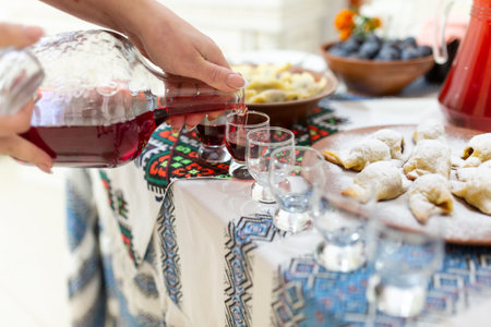 Tasting of sweet plum liqueur. A woman pours a drink from a carafe into liqueur glasses. Traditional...